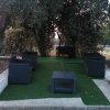 Area salotto con poltrone in vimini sotto gli alberi.