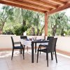 Una terrazza con tavolo apparecchiato e sedie, circondata da ulivi.
