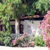 Casa bianca circondata da alberi e cespugli fioriti.