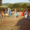 Giardino con scivolo, altalene e bambini che giocano all'aria aperta.