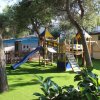 Parco giochi con erba sintetica, scivolo e altalene.