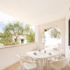 Terrazza con tavolo bianco e sedie, vista su alberi.