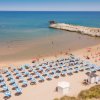 Spiaggia con ombrelloni blu e bianchi, mare calmo.