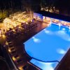Piscina illuminata di notte con sedie a sdraio.