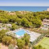 Vista aerea di un complesso con piscina e campi sportivi vicino al mare.