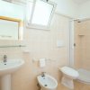 Bagno con doccia, bidet e lavabo su piastrelle chiare.