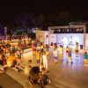 Spettacolo serale all'aperto con pubblico seduto.