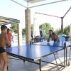 Due ragazzi giocano a ping pong, altri osservano seduti.