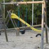 Scivolo e altalene su sabbia in un parco giochi.