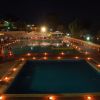 Due piscine illuminate di sera, circondate da luci e persone.