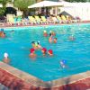 Gruppo di persone in una piscina, alcune con cuffie colorate. Lettini gialli vuoti lungo il bordo.
