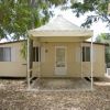 Una casa mobile beige con veranda, circondata da foglie e alberi.