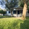 Bungalow bianco con patio, circondato da alberi e prato verde.