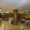 Sala da pranzo spaziosa e luminosa con tavoli, sedie e buffet al centro.
