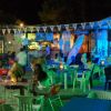 Bar all'aperto di notte con tavolini e sedie, decorato con luci colorate.