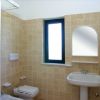 Bagno con piastrelle beige, finestra e specchio.