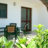 Veranda con tavolo e sedie nero, vista su giardino e albero.