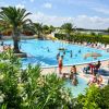 Piscina con palme e bagnanti su sdraio.