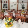 Una sala da pranzo con tavoli allestiti e fiori, foto alle pareti.