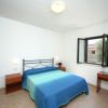Camera con letto matrimoniale, copriletto blu, finestra aperta e scrivania.
