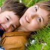 Una madre e un bambino sdraiati sull'erba, entrambi sorridenti.
