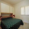 Una camera da letto con letto matrimoniale, copriletto verde e mobili bianchi.