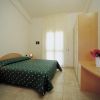 Camera da letto con letto matrimoniale, copriletto verde e arredi essenziali.