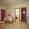 Sala da pranzo con tavolo, sedie e piccola cucina a vista.