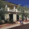 Edificio con balconi, giardino fiorito e donna con passeggino.