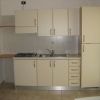 Cucina piccola con mobili beige e elettrodomestici.