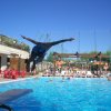 Persona che tuffa in piscina affollata.