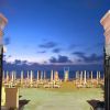 Spiaggia al tramonto con file di lettini e ombrelloni.