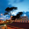 Edificio e alberi sotto cielo nuvoloso al tramonto.