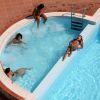 Persone rilassate in piscina con pavimento in cotto rosso.