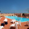 Piscina esterna con sedie bianche e cielo blu.