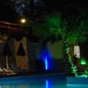 Piscina illuminata di notte, ombrelloni scuri.