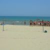 Una spiaggia con campo da pallavolo e persone che si radunano vicino all'acqua.