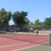 Campo da tennis all'aperto con rete e persone in gioco.