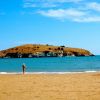 Bambino sulla spiaggia con isola erbosa di fronte.